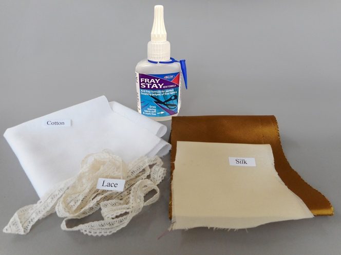 Fabrics for the outfit labelled cotton, lace and silk beside the Fray Stay bottle